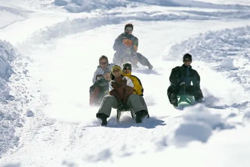 a group of people sledding down a snowy hill